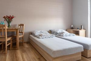 two beds in a room with a table and a dining room at Noclegi GCK Biała in Biała