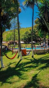 a park with hammocks between palm trees and a pool at Seleto Hotel Fazenda in Arrozal