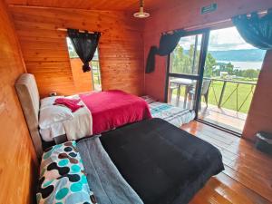 a bedroom with a bed and a large window at Cabañas finca las acacias in Guatavita