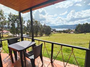 a table and chairs on a balcony with a view of a field at Cabañas finca las acacias in Guatavita