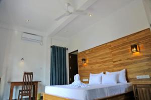 a bedroom with a large bed with a wooden headboard at Cormorant Bath in Netolpitiya