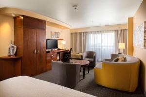 a hotel room with a bed and a couch and a desk at Courtyard by Marriott Ontario Rancho Cucamonga in Rancho Cucamonga