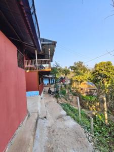 a red building next to a dirt road at Nuwakot Hills Farmstay in Trisūli Bāzār