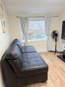 a leather couch in a living room with a window at Cozy Duplex 2nd floor suite in Winnipeg +7 photos