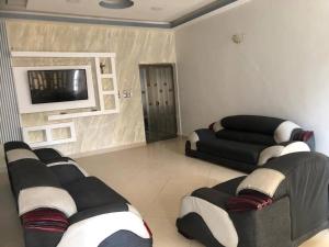 a living room with two couches and a flat screen tv at Mariagletta Cozy Villa in Abomey-Calavi