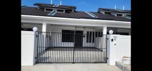 a white house with a gate in front of it at Spacious 4 bedroom homestay in Mersing