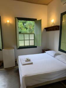 a bedroom with a white bed and a window at Pousada do Ipe in Goiás