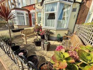 a patio with a bench and potted plants and flowers at Maluth Lodge in Great Yarmouth