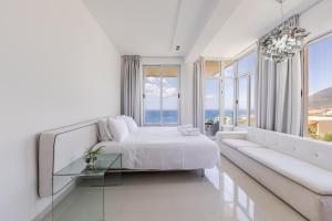 a white bedroom with a bed and a couch at Villa Belle Azure by PikHost in Dhërmi