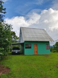 a green house with a car parked in front of it at Cinnamon Lodge in Upala