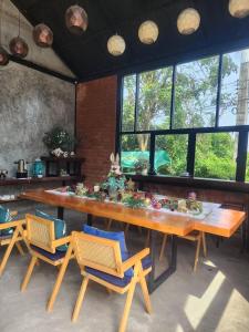 a large wooden table with chairs in a room with windows at Phumaihom Resort in Hat Yai
