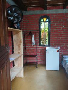 a brick room with a refrigerator and a window at Bangalo O Galo in Itacaré