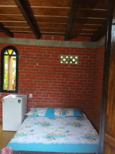 a room with a bed in a brick wall at Bangalo O Galo in Itacaré