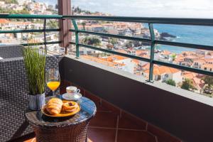 a table with a plate of food and a glass of orange juice at Villa Lobos Flat 1 in Câmara de Lobos