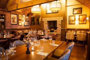 a restaurant with wooden tables and chairs and a fireplace at Tollemache Arms in Calveley