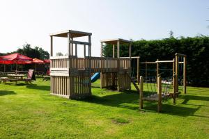 a park with two playground equipment in the grass at Tollemache Arms in Calveley