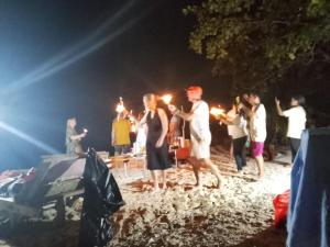 a group of people standing on a beach at night at Or Mandira Homestay in Pulau Penemu