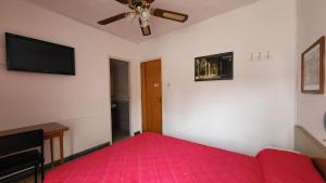 a bedroom with a red bed and a ceiling fan at Hotel Internacional Necochea in Necochea +5 photos