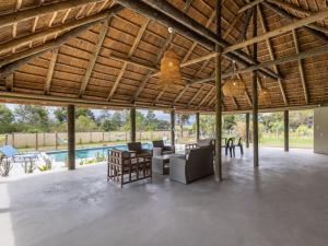 a large covered patio with furniture and a pool at Five Elements Resort - Nguni Cabin in Harkerville +3 photos