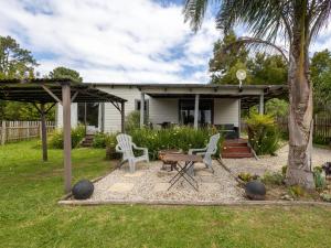 a backyard with a table and chairs and a house at Five Elements Resort - Nguni Cabin in Harkerville