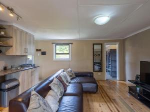 a living room with a leather couch and a kitchen at Five Elements Resort - Nguni Cabin in Harkerville