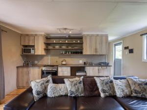 a living room with a brown couch and a kitchen at Five Elements Resort - Nguni Cabin in Harkerville