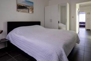 a bedroom with a bed with a white comforter at Appartement Guillaume in Blankenberge