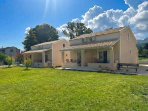 a house with a green lawn in front of it at Hestia ApartHotel in Roda