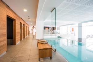 una piscina con un banco de madera en un edificio en Wellnesshotel Mein Almhof Superior, en Nauders