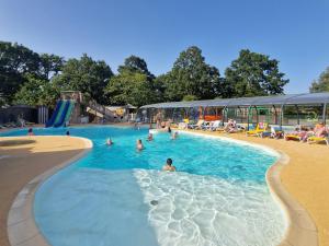 a group of people swimming in a swimming pool at Camping les Chalands Fleuris in Saint-André-des-Eaux +21 photos