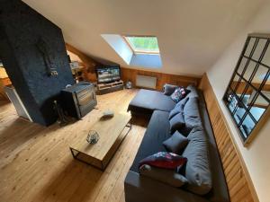 a living room with a couch and a tv at Loft des Cimes - Evasion en montagne avec local vélo privé in Cornimont