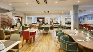 a person standing in a restaurant with tables and chairs at Sercotel HMO Martina in Granada
