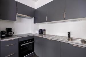 a kitchen with black cabinets and a sink at Appartement Guillaume in Blankenberge