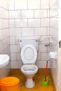 a bathroom with a white toilet with a mop at Sisama Lodge in Msaranga