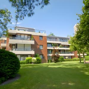 an apartment building with a lawn in front of it at Velmora Boutique Suites - Wellness - Pool, Sauna, E-Bikes direkt am Strand in Timmendorfer Strand