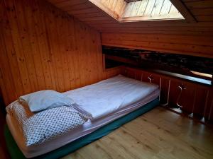 a small bed in a wooden room with a window at Lake view Chalet , Drligen in Därligen