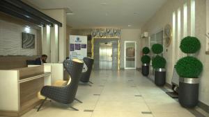 a lobby with chairs and a man sitting at a counter at 2020 Apartment Guzape in Chini