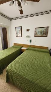 two beds in a room with green sheets at Hotel Internacional Necochea in Necochea