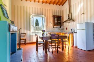 a kitchen with a table and a white refrigerator at Agriturismo Gli Archi in Fauglia
