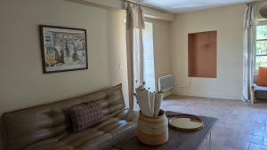 a living room with a leather couch and a table at Maison Nathis in Saint-Sulpice-de-Roumagnac