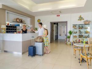 a man and woman standing at a counter with luggage at Hotel Jonio in Noto Marina