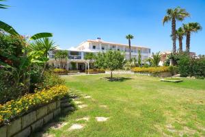 a large white building with palm trees and a yard at Hotel Jonio in Noto Marina