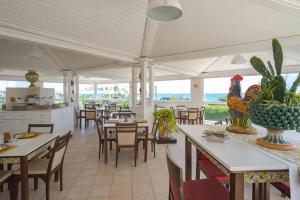 a restaurant with tables and chairs and a kitchen at Hotel Jonio in Noto Marina