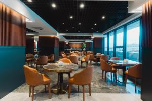 a restaurant with tables and chairs and large windows at Stillo Business Hotel & Spa in Aliağa