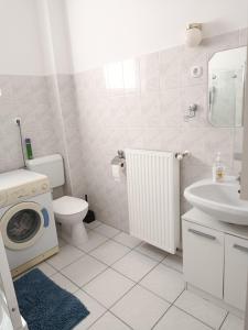 a bathroom with a toilet sink and a washing machine at Panoráma apartman in Pécs +5 photos