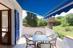 a table and chairs on a balcony with a blue umbrella at Villa Le Palme 3 - 4 in Casa Buraccio