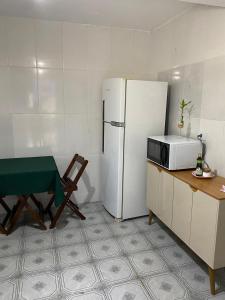 a kitchen with a refrigerator and a table and a chair at Casa no Roteiro do Vinho - Casa 02 in São Roque