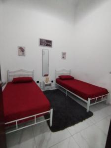 two beds in a white room with red sheets at Akiera Homestay #MELAYU ONLY in Pelabuhan Kelang