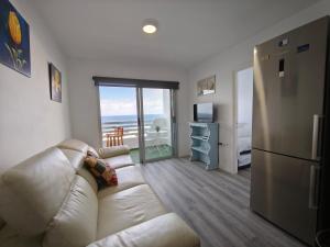 a living room with a couch and a desk with a television at Sunset living area in Puerto de la Madera