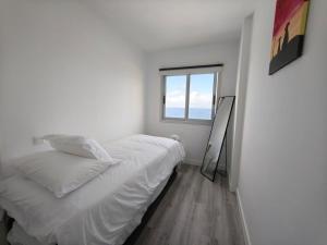 a white bedroom with a bed and a window at Sunset living area in Puerto de la Madera
